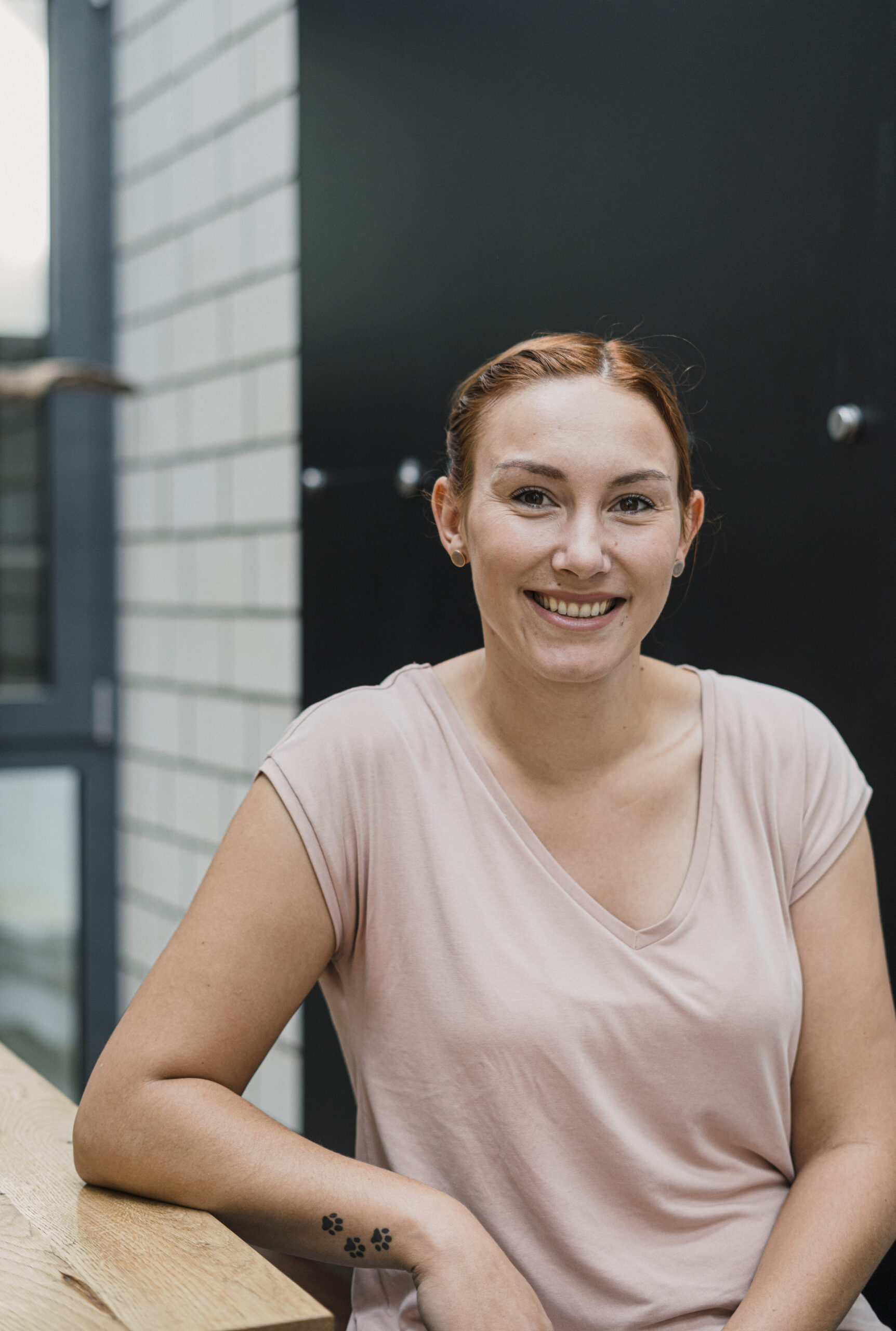 Portraitfoto von unserer Projekt Managerin Juliane Sulzbacher. Sie lächelt freundlich in die Kamera, während sie an einem Tisch sitzt.